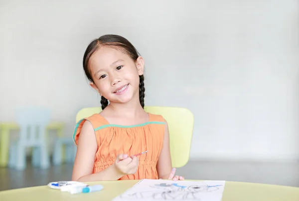 子供の部屋で紙に水の色で描くと絵の愛らしい小さなアジアの女の子 — ストック写真