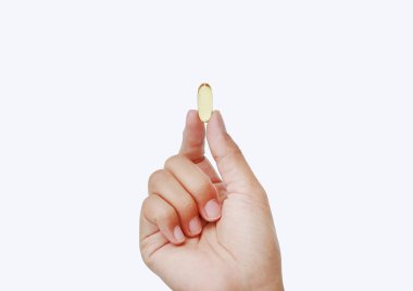 El ele tutuşan sarı balık yağı kapsülü beyaz arka planda izole edilmiş.