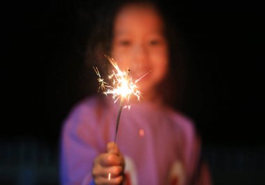 Küçük Asyalı çocuk kız zevk havai fişek oynuyor. Yangın maytap odak.