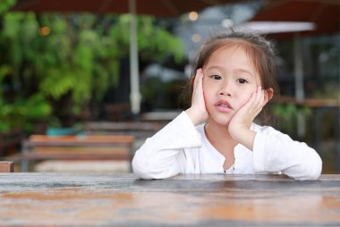 Huzurlu sevimli küçük Asyalı çocuk kız şık ahşap masanın üzerinde yatan sen.