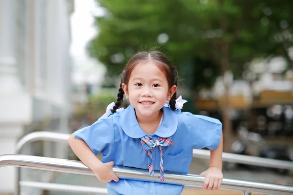 Счастливая Маленькая Азиатка Школьной Форме Игривая Висит Металлических Перилах — стоковое фото