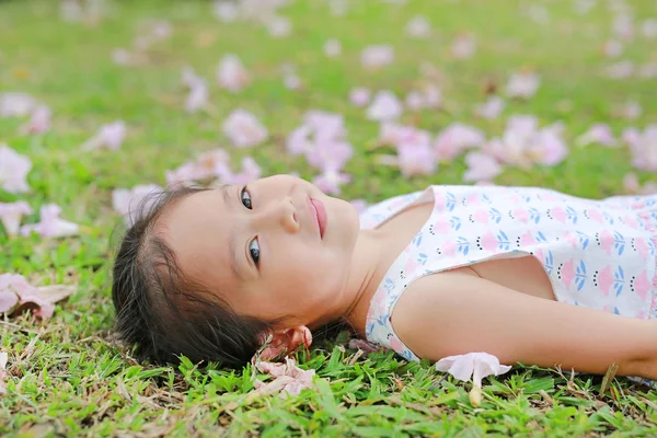 Sorrindo Menina Deitada Grama Verde Com Queda Flor Rosa Jardim — Fotografia de Stock