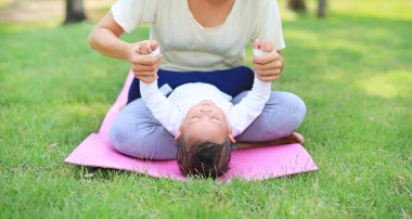 Asyalı anne oğlu ile oynarken ve parkta yeşil çim üzerinde yalan.