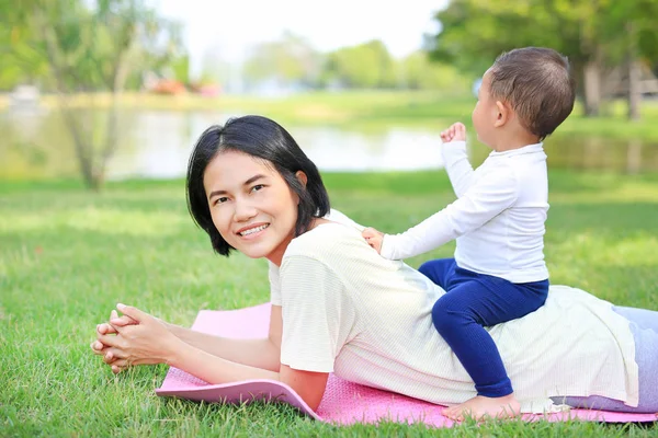 Happy family Asian mom and her son lying on green lawn background.