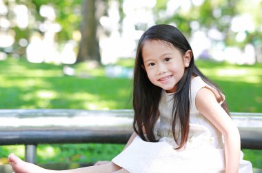 Doğa parkta küçük gülümseyen Asya çocuk kız.