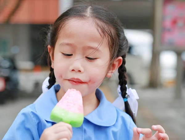身着校服的亚洲小女孩在吃冰淇淋的肖像 — 图库照片
