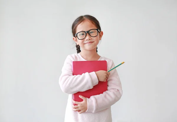 眼鏡をかけたアジアの女子高生が本を抱きしめ 白い背景に鉛筆を手に持つ カメラをまっすぐに見つめている少女の肖像画 — ストック写真