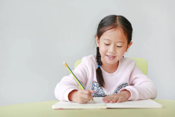 Felice Bambina Asiatica Scrive Libro Taccuino Con Matita Sul Tavolo — Foto Stock