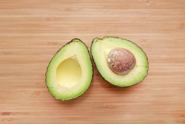 Ahşap tahta arka planda ikiye kesilmiş avokado.