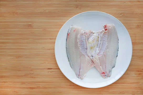 コピー スペースで木の板の背景に白い皿の上生ティラピア魚の切り身 — ストック写真