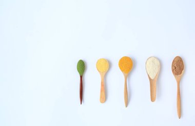 Beyaz arka plan üzerinde izole kopya alanı ile farklı ahşap kaşık çeşitli renkli toz.