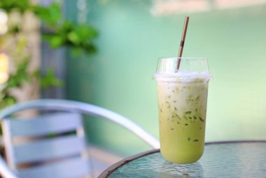 Doğa bahçe arka plan karşı masa ve sandalye üzerinde süt ile buzlu yeşil çay matcha latte.
