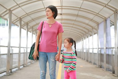 Asyalı anne üst geçitte yürürken kızını el ele tutuşuyor. Mon ve çocuk kız birlikte yürümek.