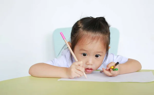 白い背景にテーブルの上に鉛筆の書き込み紙と学校の制服を着たアジアの子供 — ストック写真