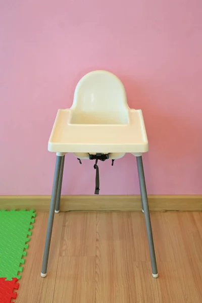 High chair. Plastic feeding chair in the playroom.