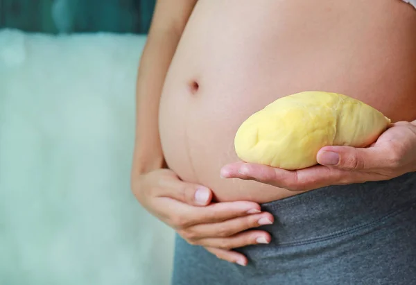 怀孕妇女抱着榴莲在她的腹部 节食的概念 — 图库照片