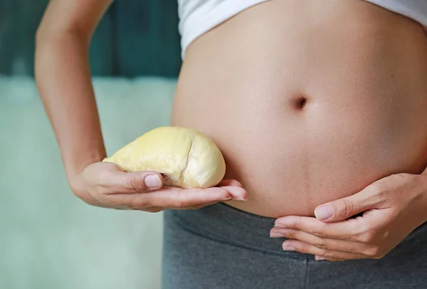 怀孕妇女抱着榴莲在她的腹部 节食的概念 — 图库照片