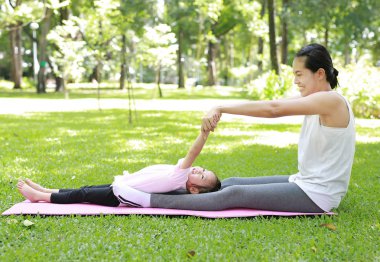Hamile anne ve kızı genel parkta yoga yaparken.