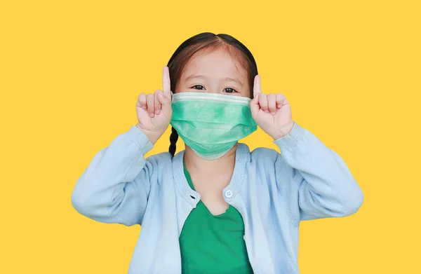 Ázsiai Kislány Visel Védő Maszkot Mutató Két Mutatóujj Izolált Sárga — Stock Fotó