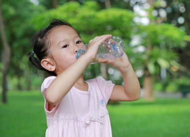 Parktaki şişeden su içen küçük kız. Açık havada portre