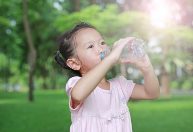 Parktaki şişeden su içen küçük kızı kapat. Açık havada portre.