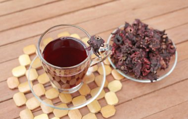 Bir bardak Roselle suyu ve ahşap zemin üzerinde kurutulmuş roselle..