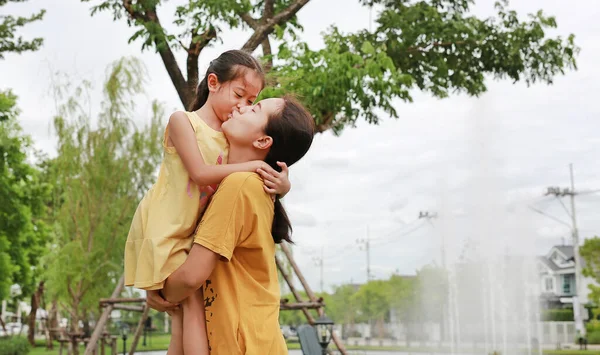 公園でリラックスしたアジアの母親と娘の肖像画 ママ運ぶ彼女の子供の女の子で公共の庭 — ストック写真