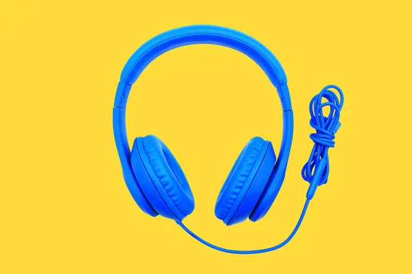 黄色の背景に隔離された青いヘッドフォン 音楽的対象概念 — ストック写真