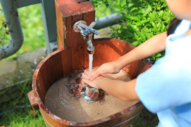 Yakın plan Asyalı küçük kız ellerini lavaboda yıkıyor..
