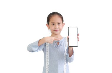 Akıllı telefon tutan güzel Asyalı küçük kız ve beyaz arka planda izole edilmiş beyaz ekrana işaret ediyor..