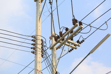 Beton kutuptaki elektrik kabloları gökyüzü arka planına karşı.