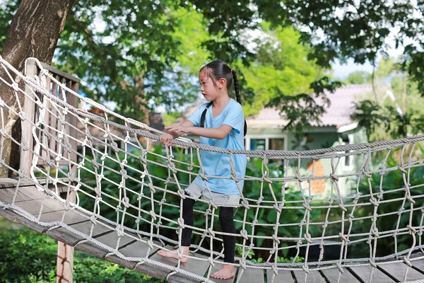 サスペンション木製の橋で遊んでアジアの小さな子供の女の子 ロープブリッジを歩く子供公園の遊び場での設備 — ストック写真