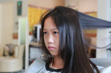 Kuaförde Asyalı ergen kızın saçını kurutup tarayan profesyonel stilistin portresi. Yakın çekim..