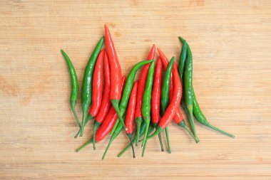 Bambu ahşap arka planda kırmızı ve yeşil kırmızı biber, pişirme için kırmızı biber hazırlama süreci. Üst görünüm.