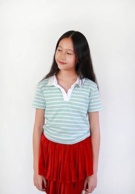 Beyaz arka planda dururken gülümseyen Asyalı kız. Çocuk özgüveni tatlı ve şık görünüyor..