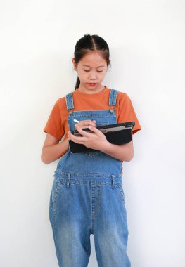 Asyalı kız elinde tablet ve stil tutarken beyaz arka plana karşı yaratıcı ya da eğitici bir proje üzerinde çalışıyor, yazıyor ya da çiziyor..