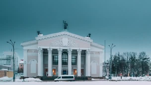 Гомель, Білорусь. Час минає від дня до ночі. Трафік і легкі стежки біля будівлі Гомельського обласного драматичного театру На площі Леніна в зимовий сезон. Зміна дня на ніч — стокове відео