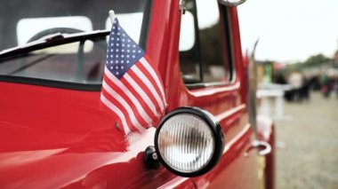 Ağır çekimde dalgalanan küçük Amerikan bayrağı taşıyan Kırmızı Kamyonun Yan Görünümü