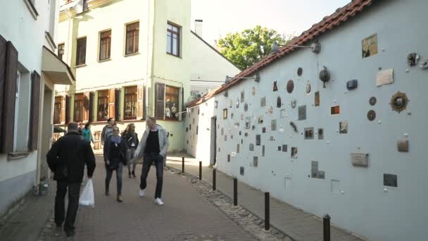 Vilnius, Litva - 29. září 2017: People Walking near Literatu Street - One of The Oldest Streets In The Old Town of Vilnius, Lithuania. Stěna literárních uměleckých děl. Literatu Street Wall — Stock video