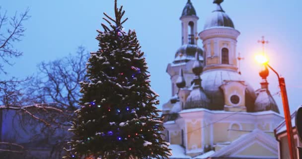 Parnu, Estonia. Árbol de Navidad en vacaciones Año Nuevo Iluminación festiva y la iglesia ortodoxa de Santa Catalina en el fondo — Vídeos de Stock