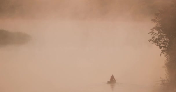 Sakin göl, nehir ve yaşlı ahşap kürek balıkçı teknesinde balık tutan adam yaz sabahı sisli gündoğumunda. Balıkçı ahşap bir teknede. Rus Doğası — Stok video