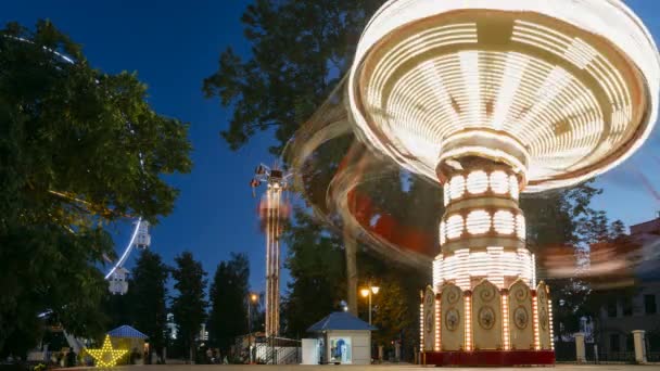 Helder verlichte draaiende draaibare draaibare draaimolen met hoge snelheid. Zomer avond in het pretpark van de stad — Stockvideo