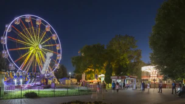 Draaien in verlichte attractie Ferris wiel en helder carrousel Merry-Go-Round op de zomeravond in de stad pretpark — Stockvideo