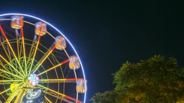 Girando no efeito natural do movimento iluminou a roda gigante da atração na noite no parque de diversões da cidade — Vídeo de Stock
