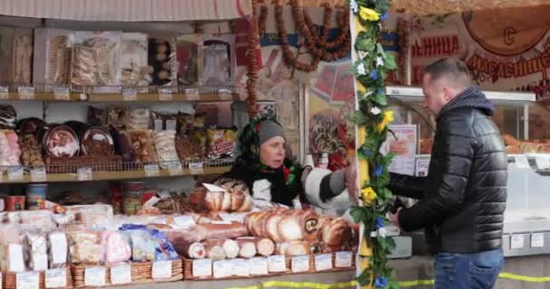 Gomel, Belarus - 18 februari 2018: Vrouw gekleed in nationale volkskleding Handel in gebak, brood, broodjes tijdens de viering Oost-Slavische Nationale Traditionele Vakantie Maslenitsa. Winter voorjaarsvakantie — Stockvideo