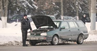 Gomel, Belarus - 2 Mart 2018: Adam kış günü bozuk arabanın yanında cep telefonundan arıyor