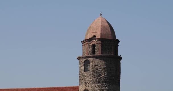Collioure, Frankrijk. Kantel uitzicht op de kerk van Onze Lieve Vrouw van de Engelen aan de overkant van de baai in de zonnige Lente Dag — Stockvideo