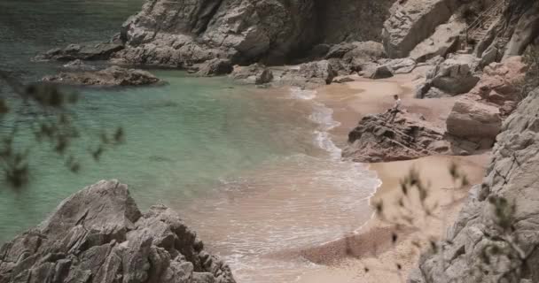 Jeune homme caucasien adulte assis dans la pierre de roche et profiter de la vie sur la plage de l'océan de mer d'été en Espagne — Video
