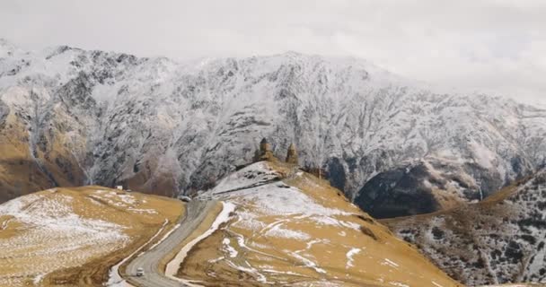 Stepantsminda, Gergeti, Georgia. Famosa iglesia de Gergeti Trinity Tsminda Sameba en el paisaje de finales de otoño. Hermoso paisaje georgiano de la naturaleza del invierno — Vídeos de Stock