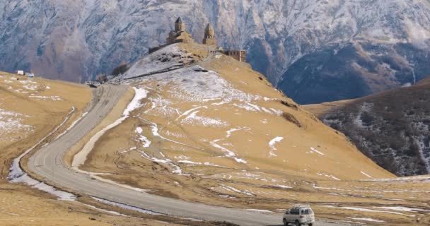 Stepantsminda, Gergeti, Georgia. Famosa iglesia de Gergeti Trinity Tsminda Sameba en el paisaje de finales de otoño. Hermoso paisaje georgiano de la naturaleza del invierno — Vídeos de Stock